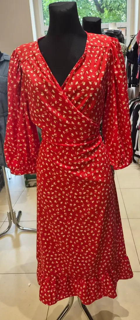 Ein rotes Wickelkleid mit kleinem Blumenmuster an einer Puppe