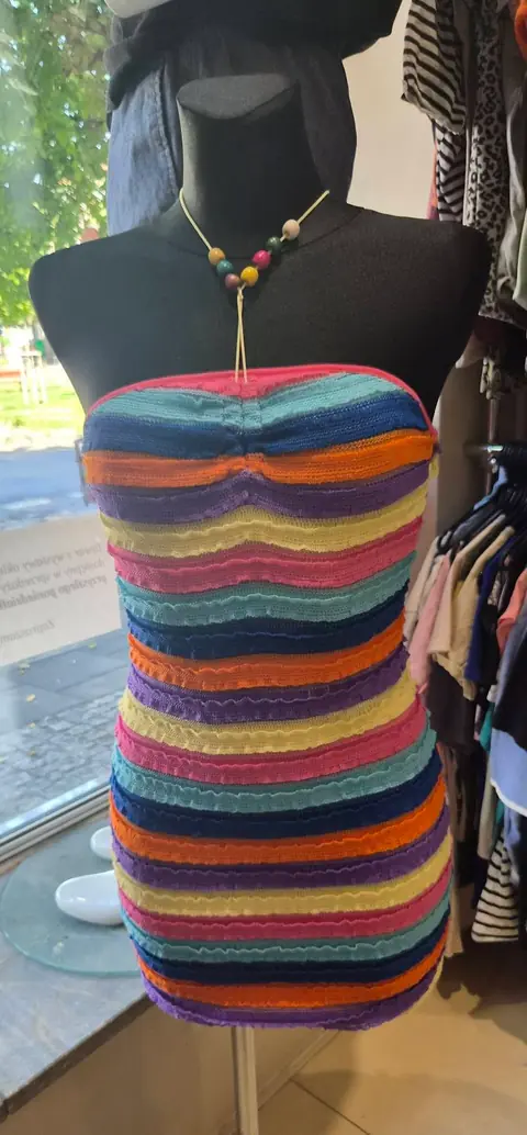 Ein figurbetontes Kleid mit bunten Querstreifen und einer Perlenkette