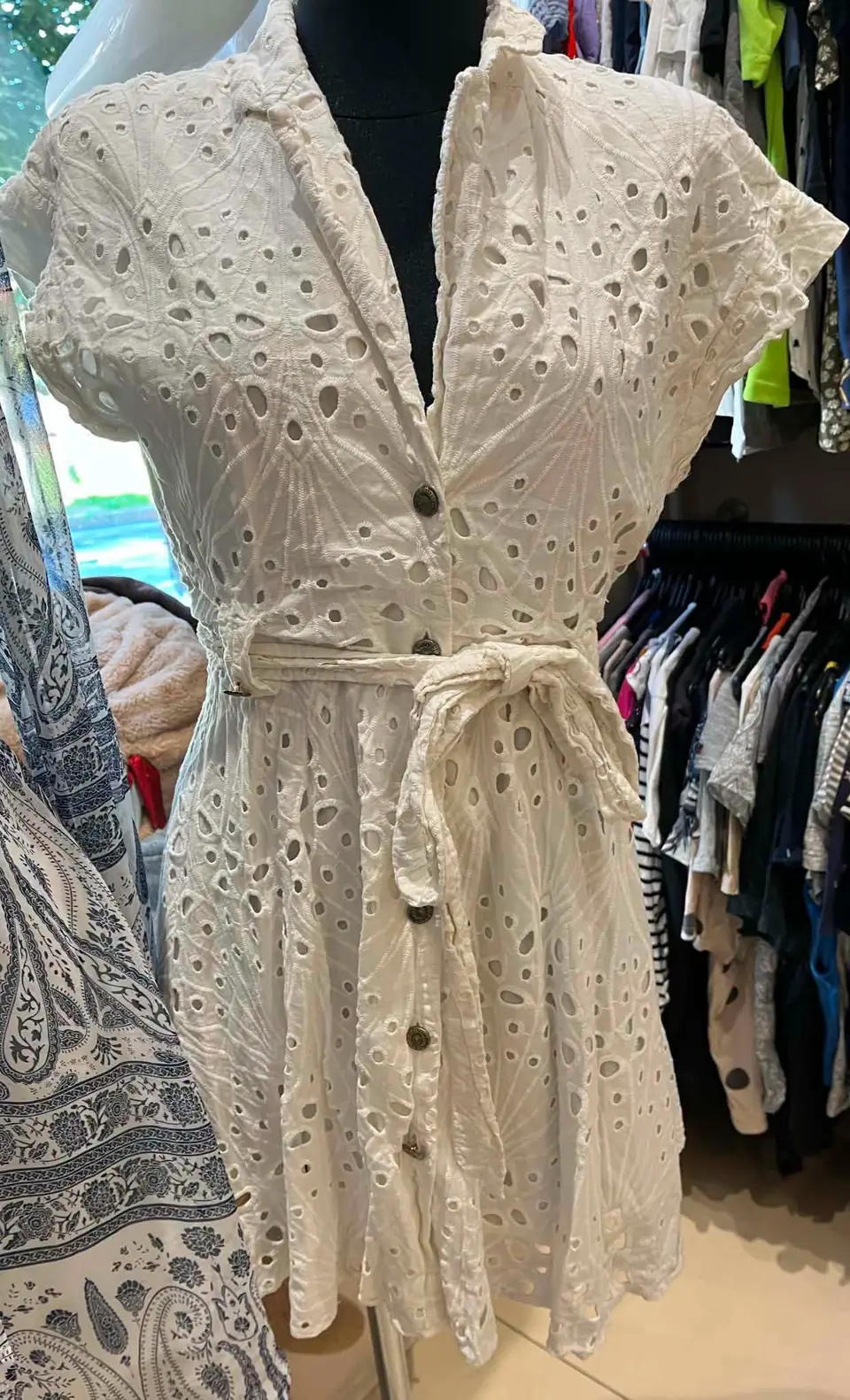 Ein weißes Ajourkleid mit kurzen Ärmeln, in der Taille gebunden