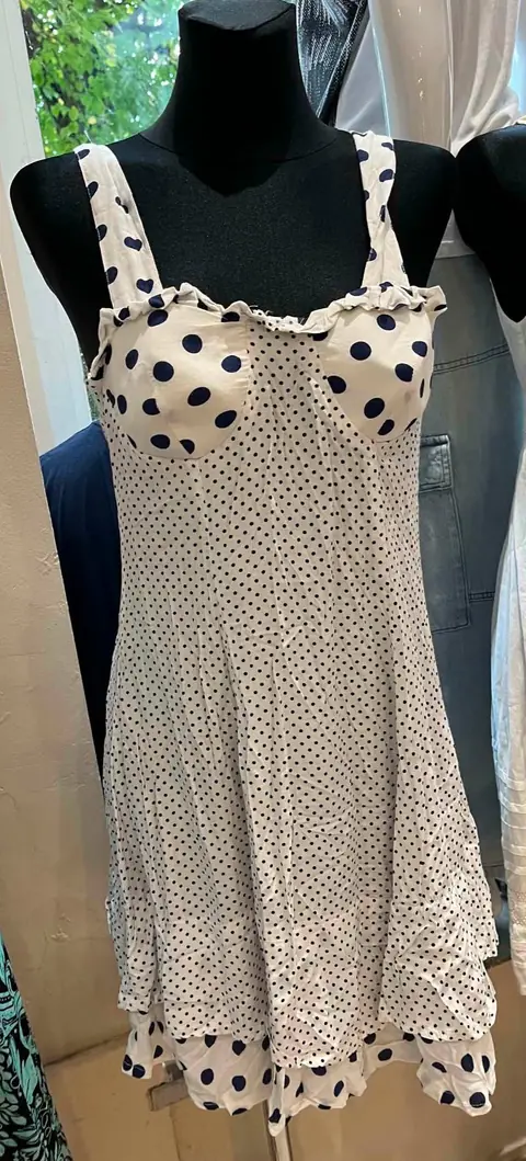 Ein cremefarbenes Trägerkleid mit schwarzen Punkten und Volantsaum