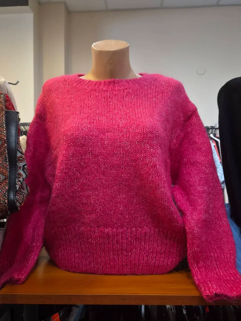 Ein flauschiger rosa Mohairpullover auf einem Tisch