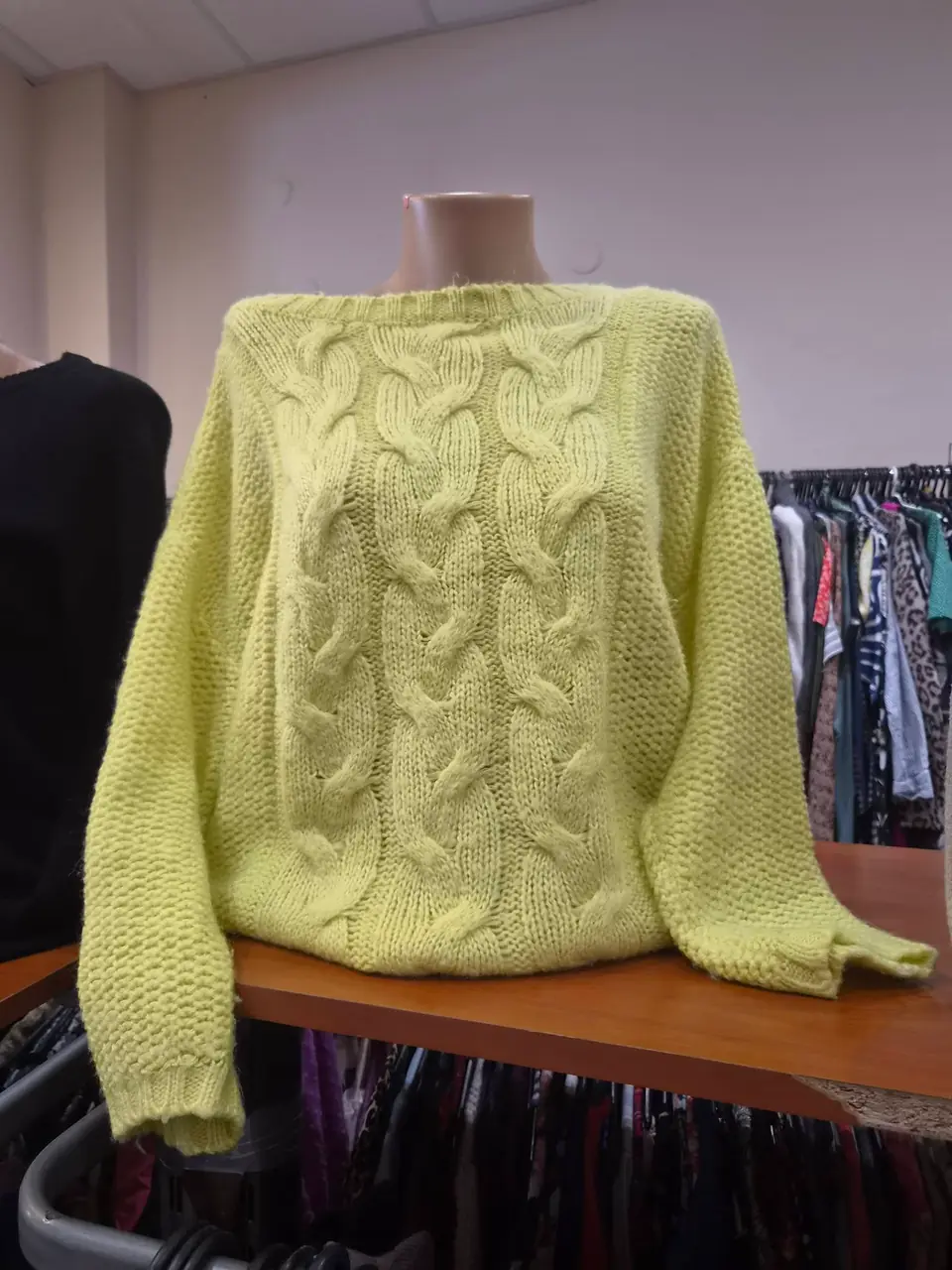 Ein limettengrüner Zopfmusterpullover auf einem Tisch