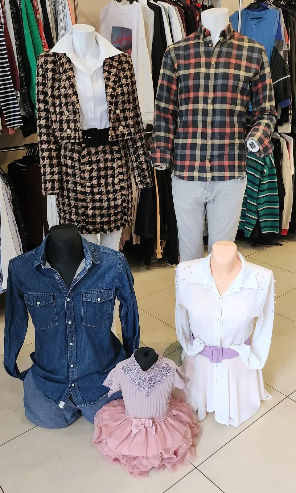Ladenauslage: karierte Hemden, ein Jeanshemd und weiße Kinderkleider
