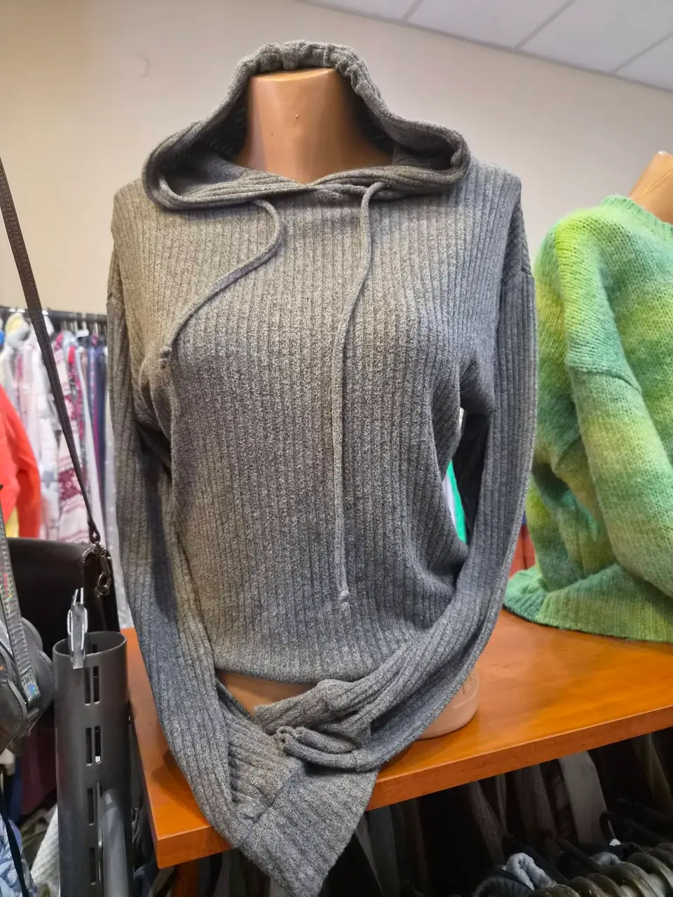 Ein grauer Kapuzenpullover in Rippstrick, daneben ein grüner Pullover
